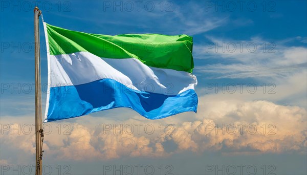 The flag of Sierra Leone, fluttering in the wind, isolated, against the blue sky