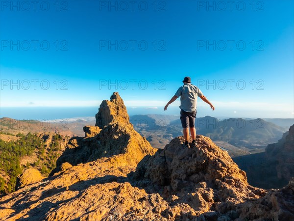 A tourist man with open arms on the top of Pico de las Nieves in Gran Canaria, Canary Islands