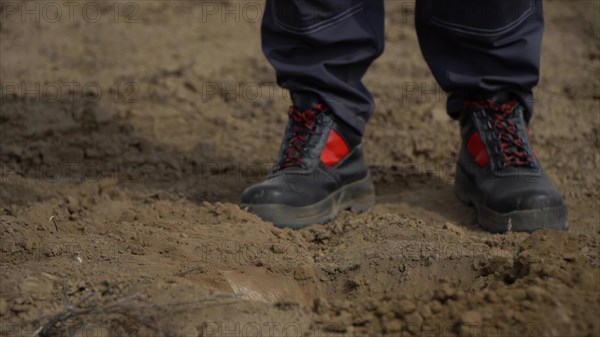 Close up of human feet in black shoes on muddy ground