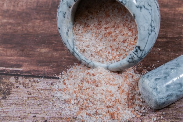 Himalayan pink salt in a ceramic mortar on a wooden table with a copy space