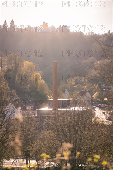 Industrial chimney rises into a sky at sunset with trees, spring, Calw, Black Forest, Germany, Europe