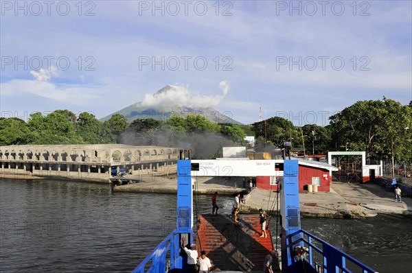 Lake Nicaragua, Ferry on the shore of a lake with an active volcano in the background and cloudy sky, Nicaragua, Central America, Central America