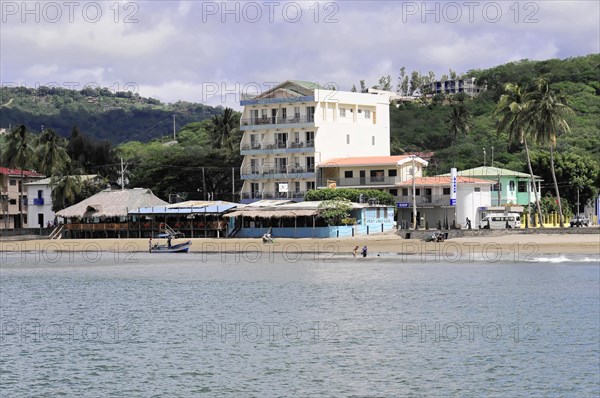 San Juan del Sur, Nicaragua, A view of the shore with a multi-storey building next to palm trees and beach, Central America, Central America