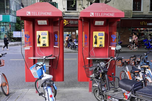 Shanghai, China, Two red telephone booths on a pavement next to parked bicycles, Shanghai, People's Republic of China, Asia
