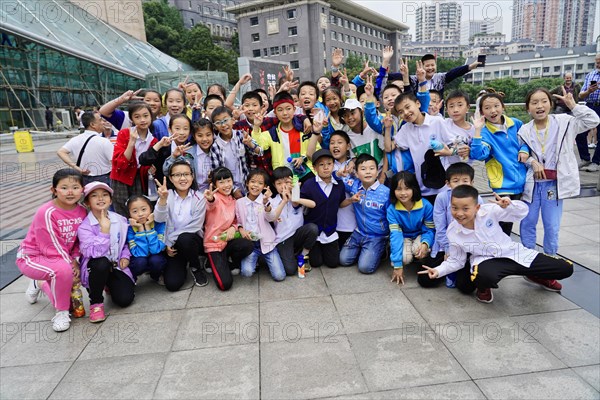 Chongqing, Chongqing Province, China, Asia, A group of smiling children showing Victory signs, urban background, Asia