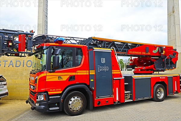 A red fire engine with a turntable ladder is parked in front of a stadium