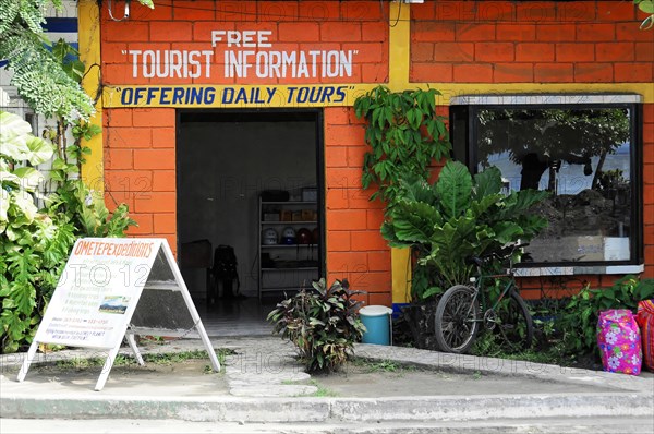 Ometepe Island, Nicaragua, A red building with signs for tourist information and daily tours, flanked by plants, Central America, Central America