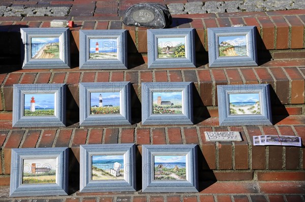 Westerland, Sylt, Schleswig-Holstein, Germany, Europe, Several framed paintings of lighthouses and beach scenes displayed on a tiled floor, North Frisian Island, Schleswig Holstein, Europe