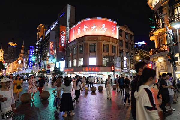 Evening stroll through Shanghai to the sights, Shanghai, Large city square at night with illuminated advertising on the facades and people chatting, Shanghai, People's Republic of China