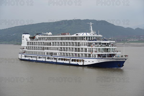 Cruise ship on the Yangtze River, White and blue cruise ship on a river with a slightly cloudy sky in the background, Yangtze River, Chongqing, Chongqing Province, China, Asia