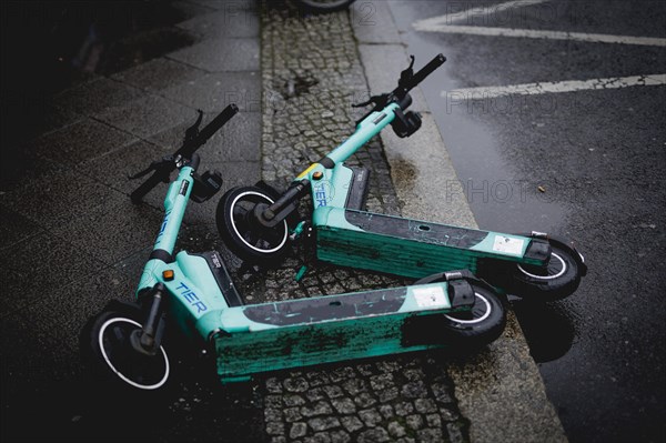 Two e-scooters lying on the road in the rain, taken in Berlin, 19/04/2024
