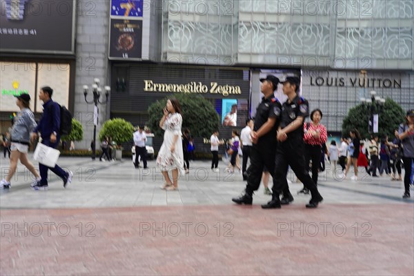 Chongqing, Chongqing Province, China, Asia, A police patrol walks through a shopping district, past luxury shops, Asia