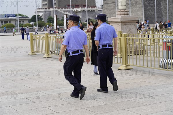 Beijing, China, Asia, Two uniformed security guards walk on a paved square in an urban neighbourhood, Asia