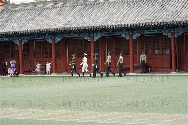 China, Beijing, Forbidden City, UNESCO World Heritage Site, A line of marching soldiers in front of traditional Chinese buildings and a red poster, Asia