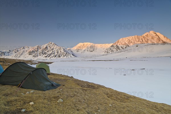 Icy tents in expedition camp at sunrise over the mountain peaks in the snow-covered Tavan Bogd National Park, Mongolian Altai Mountains, Western Mongolia, Mongolia, Asia