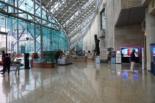 Chongqing, Chongqing Province, China, Asia, Modern lobby of a building with glass structures and a sculpture, people walking around, Asia