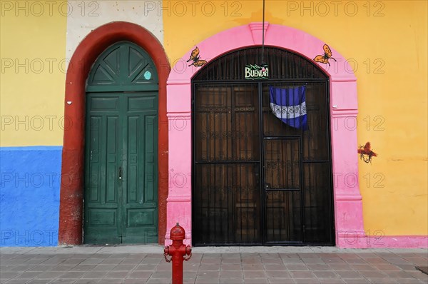 Granada, Nicaragua, The vividly colourful facade of a building with a large wooden door and butterfly decorations, Central America, Central America -, Central America