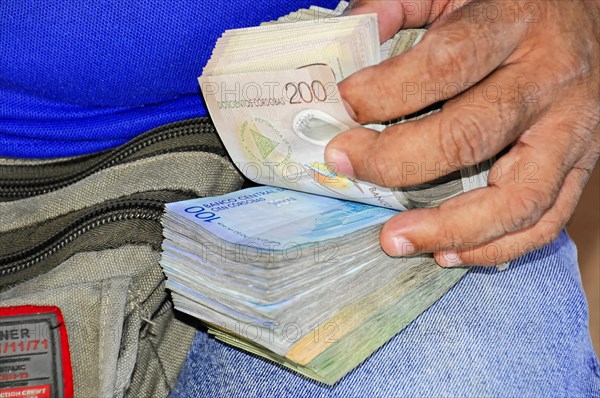 Leon, Nicaragua, hands counting Honduran Lempira banknotes in front of an open bag, Central America, Central America