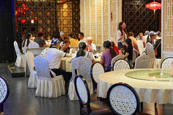 Dinner at posh restaurant in Shanghai, China, Asia, People enjoying a meal on a restaurant terrace surrounded by elegance and soft lighting, Shanghai, Asia