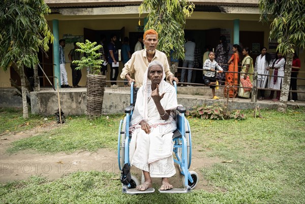 BOKAKHAT, INDIA, APRIL 19: A elderly woman in wheelchair show her marked finger after casting vote during the first phase of the India's general elections on April 19, 2024 in Bokakhat, Assam, India. Nearly a billion Indians vote to elect a new government in six-week-long parliamentary polls starting today