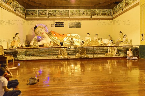 Shwedagon Pagoda, Yangon, Myanmar, Asia, Reclining Buddha statue in a temple, surrounded by praying people in a contemplative atmosphere, Asia