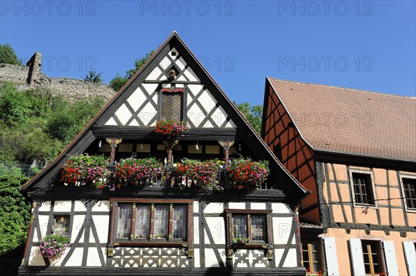 Kaysersberg, Alsace Wine Route, Alsace, Departement Haut-Rhin, France, Europe, A traditional half-timbered house with a flower-covered balcony under a clear blue sky, Europe