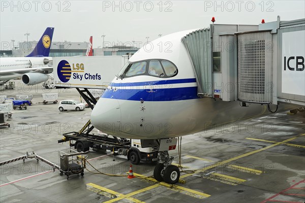 Flight CA 936 Frankfurt, Shanghai China, front view of a parked aircraft with catering vehicle at the airport gate under overcast sky, Shanghai, China, Asia