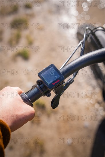 A hand operates a bicycle speedometer on the handlebars of a bicycle near a cycle path, spring, e-bike forest bike, Gechingen, Black Forest, Germany, Europe