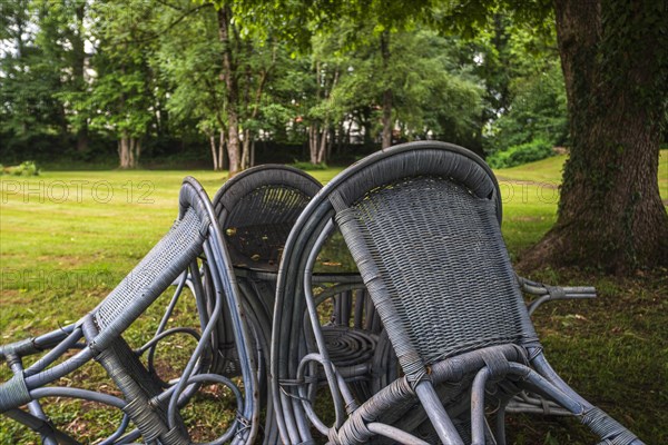 Four chairs are grouped around a table under a tree in a park, St George's Monastery, Isny im Allgaeu, Baden-Wuerttemberg, Germany, Europe