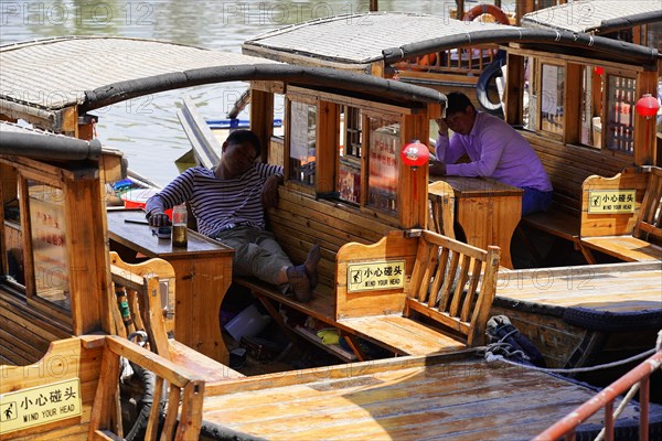 Excursion to Zhujiajiao water village, Shanghai, China, Asia, wooden boat on canal with view of historical architecture, passengers relaxing on a boat at the dock on a river, Asia