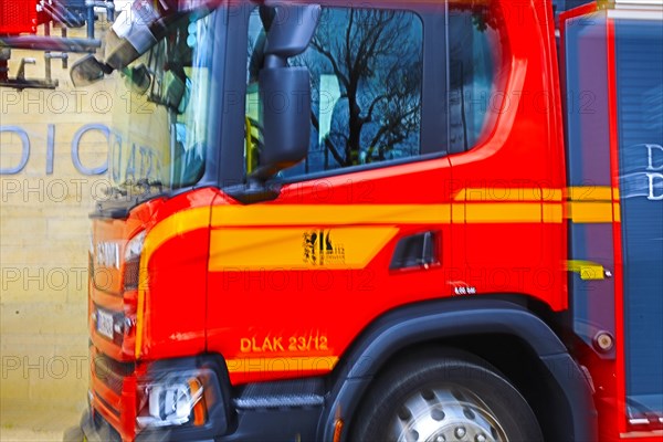 Side view of a red turntable ladder fire engine with yellow stripes