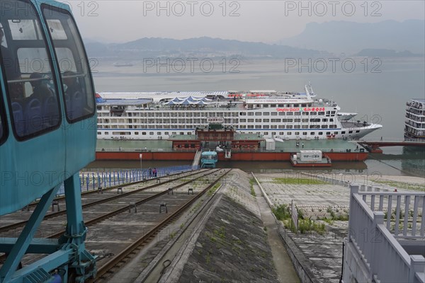 Cruise ship on the Yangtze River, Yichang, Hubei Province, China, Asia, A lift on rails in front of a cruise ship on the river bank, mountains in the background, Shanghai, Asia