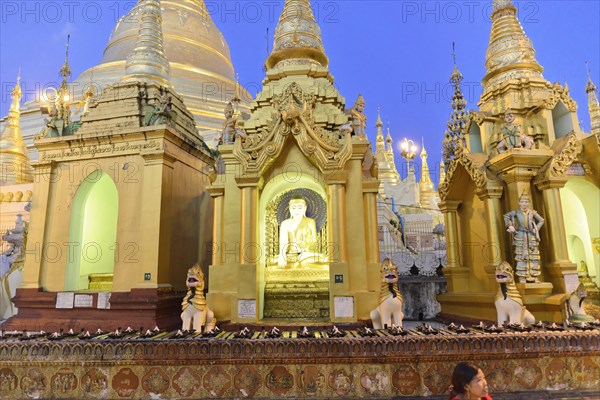 Shwedagon Pagoda, Yangon, Myanmar, Asia, A Buddha statue in front of the gilded structures of the Shwedagon Pagoda at night, Asia
