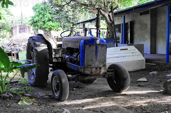 Ometepe Island, Nicaragua, An old, blue tractor stands in front of rural buildings, Central America, Central America