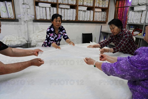 Silk factory Shanghai, Several workers stretching a large length of fabric together, Shanghai, China, Asia