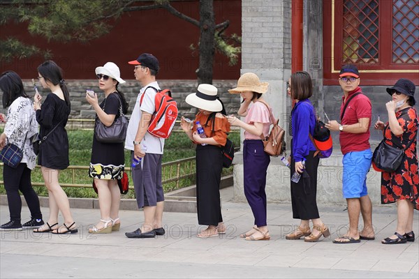New Summer Palace, Beijing, China, Asia, Tourists in summer clothes stand in a queue next to a historic red wall, Beijing, Asia