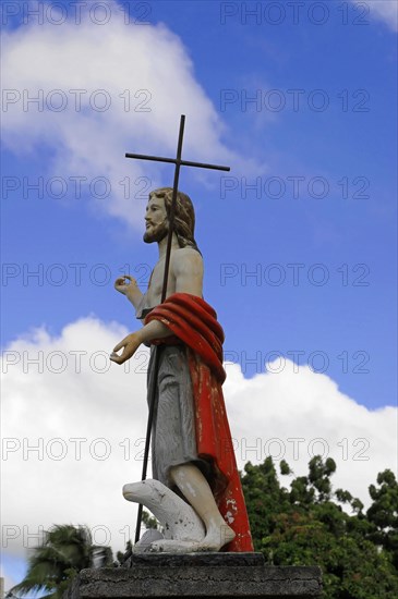 Church of San Juan del Sur, Nicaragua, Central America, Statue of Jesus Christ with a cross in front of a blue sky with clouds, Central America