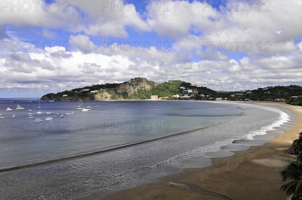 San Juan del Sur, Nicaragua, Clear waves rolling towards a beach with a bay full of yachts in the background, Central America, Central America