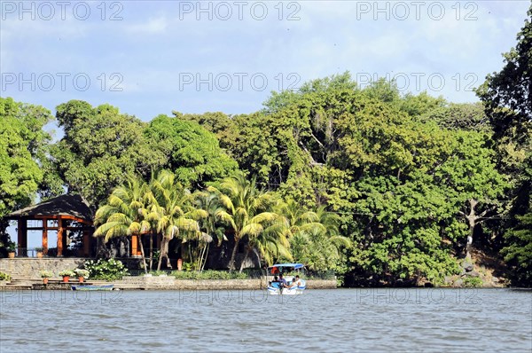 Granada, Nicaragua, View of Lake Nicaragua with a small boat surrounded by palm trees and a pavilion on the shore, Central America, Central America