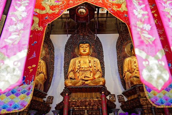 Jade Buddha Temple, Shanghai, Buddha in meditation posture behind colourful curtains on a richly decorated altar, Shanghai, China, Asia