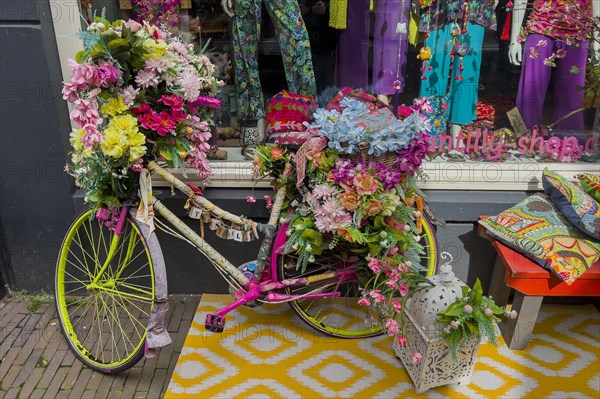 Colourful decorated bicycle in front of a fashion shop, decoration, whimsical, funny, hippie, hippie look, vintage, design, seventies, colourful, flashy, fashion, shop, shop, shopping, shopping, tourism, urban, city trip, travel, flowers, decorated, shop window, Deventer, Netherlands