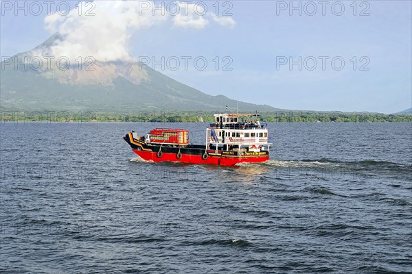 Lake Nicaragua, in the background the island of Ometepe, Colourful ferry on the lake, transporting vehicles with a volcano in the background and partly cloudy sky, Nicaragua, Central America, Central America