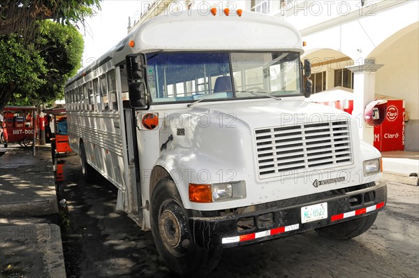 Leon, Nicaragua, White school bus parked on the roadside under trees in an urban area, Central America, Central America