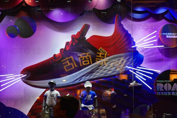 Evening stroll through Shanghai to the sights, Shanghai, Large advertising sign for sneakers with glowing light effects in the shop window, Shanghai, People's Republic of China