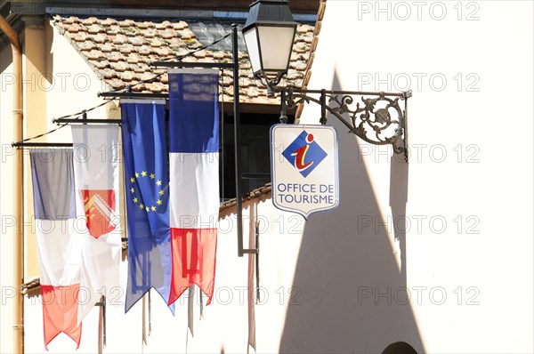 Eguisheim, Alsace, France, Europe, Flags in front of a tourist information centre cast shadows on the wall, Europe