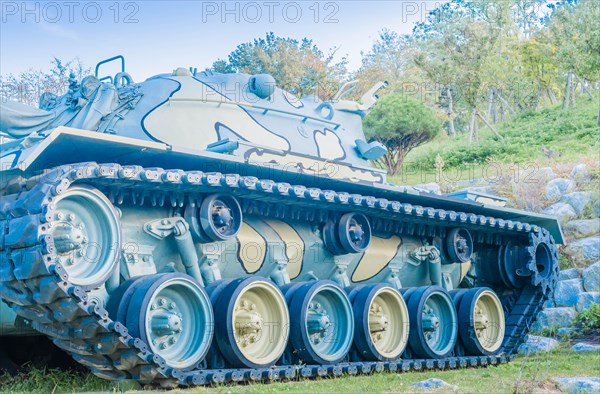 Side view of army tank in camouflage paint on display in public military history park on sunny afternoon in Nonsan, South Korea, Asia