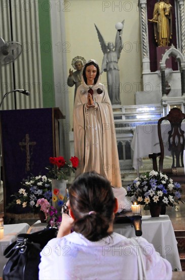 Church Iglesia de Guadalupe, built 1624 -1626, Granada, Nicaragua, Person praying in front of a religious statue surrounded by flowers, Central America, Central America -, Central America