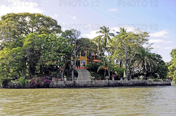 Granada, Nicaragua, Colourful house on the lakeshore with a boat in front, surrounded by palm trees, Central America, Central America