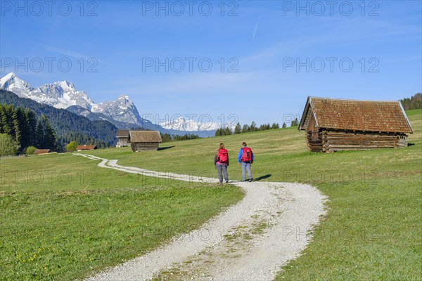 Two hikers at Geroldsee or Wagenbruechsee, Estergebirge with huts, Kruen near Mittenwald, Werdenfelser Land, Upper Bavaria, Bavaria, Germany, Europe