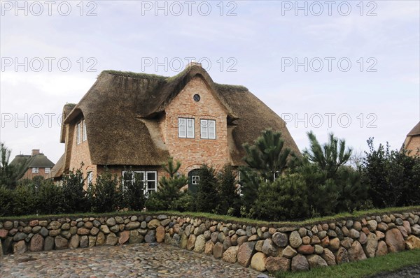 Sylt, North Frisian Island, Schleswig Holstein, A large thatched house behind a stone wall on an overcast day, Sylt, North Frisian Island, Schleswig Holstein, Germany, Europe